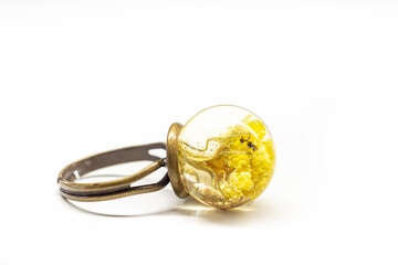 Handmade yellow flower ring. Brass base, Helichrysum bracteatum plants inside epoxy resin, romantic gift idea. Selective focus on the details, blurred background.