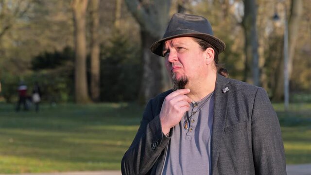 [4k] middle aged man wearing hat doing hard thinking at park