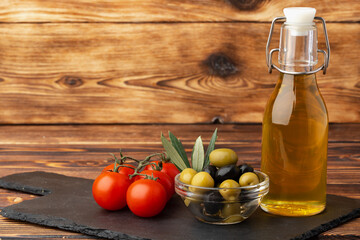 Olive oil, olives and tomatoes on wooden background