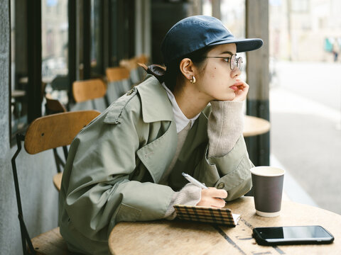 カフェのテラスで勉強をする帽子を被った女性