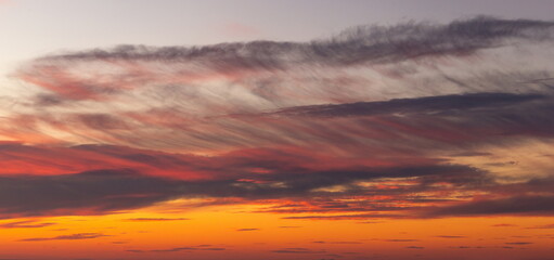 Real sunset sky with gentle colorful clouds without birds. Natural background.