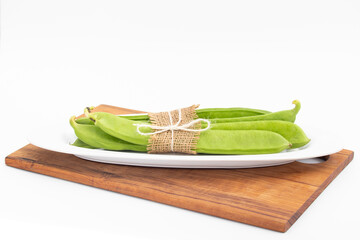 Flat Long Green Vegetable Runner Beans Known As Jhar Sim, Falia, Keralan, Sem Ki Phali, Surti Papdi, Guar Ki Fali, Gawar Isolated On White Background. Used To Cook Curry Bhaji Sabji Or Hari Sabzi - obrazy, fototapety, plakaty