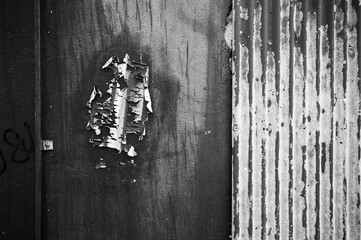 Black and white peeling paint on concrete wall and corrugated iron
