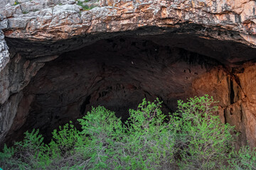 Akmeshit or Akmechet cave. Huge cavern with hole and green trees groving under.