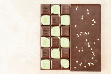 Brown and green fruit chocolate bars on black background. Handmade chocolate with mango, orange flavor. Healthy food concept, delicious chocolate sweets for kids, diet, sugar