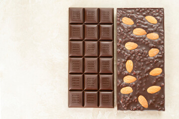 assortment chocolate bars with almonds, handmade sweets. Composition of bars milk and dark almond chocolate on black background, top view. Pastry craft on the table