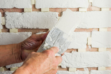 the master applies the adhesive solution with a spatula to the decorative tile. concept of finishing works.