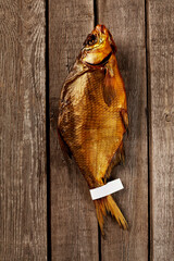 Whole smoked bream with label on tail on rough wooden boards background