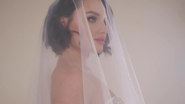Close-up portrait of a bride in a dress with a veil that covers her head. Happy wedding day.