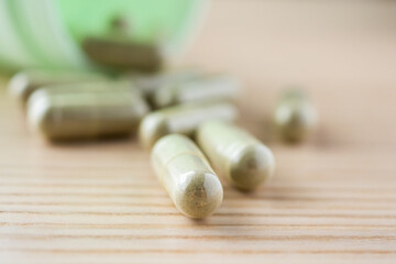 Fototapeta na wymiar Herbal medicine capsules with bottle on wood table
