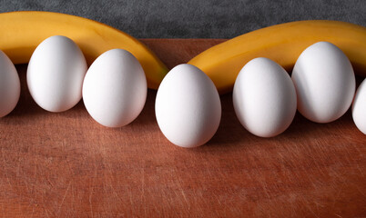 ripe fresh bananas with eggs on wooden board