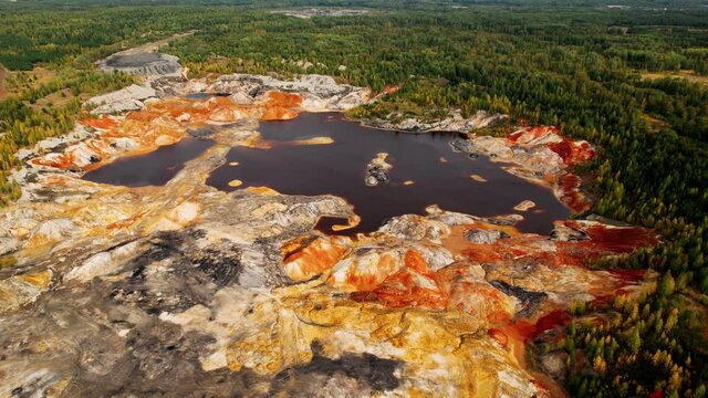 Dried dead plants in the middle of an acidic orange lake. An industrial copper mine pollutes the environment. The soil is contaminated with heavy metals from industrial plants. Aerial view