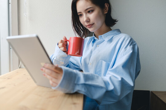 赤いコップと女性とタブレット