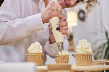 confectioner squeezes out a white cream in the form of roses flowers. process of decorating...