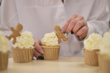 confectioner squeezes out a white cream in the form of roses flowers. process of decorating cupcakes with white whipped cream. Decorating a white cake with cream from the pastry bag.