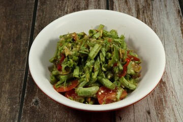 Traditional spicy string bean salad (Green Yard long bean) dressing with pickled fish sauce serving in the bowl. Famous local street food menu in Asia.