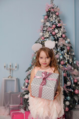 Smiling child girl under Christmas tree with decorations in room.