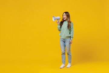 Full body young woman 30s wearing green knitted sweater hold scream in megaphone announces discounts sale Hurry up isolated on plain yellow color background studio portrait. People lifestyle concept.