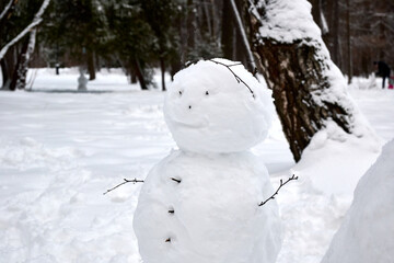 Snowman in winter park close up among trees