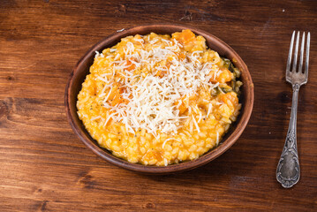 Serving of pumpkin risotto in a plate sprinkled with grated Parmesan cheese