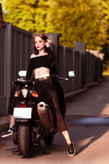 Young Caucasian Female Biker Leaning on Sport Bike Back To Front Outdoors.