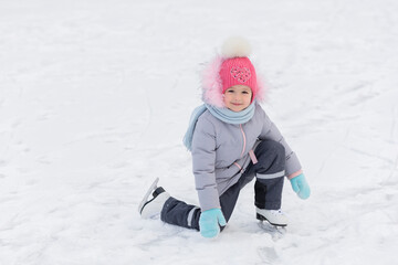 Fototapeta na wymiar little girl learning ice skating in park on rink. children winter sport. outdoor games, pastime wintertime. kids with skates on cold freezing day. Snow outdoor fun for child. Christmas family vacation