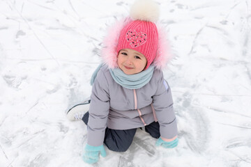 little girl learning ice skating in park on rink. children winter sport. outdoor games, pastime...