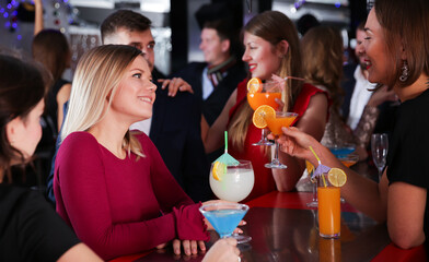 Portrait of happy young woman with colleagues enjoying corporate party in bar