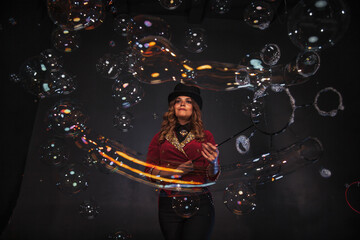 Obraz na płótnie Canvas Female magician makes with soap bubbles show, an illusionist