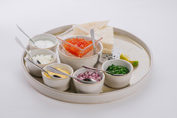 Dish with red caviar and herbs on white background