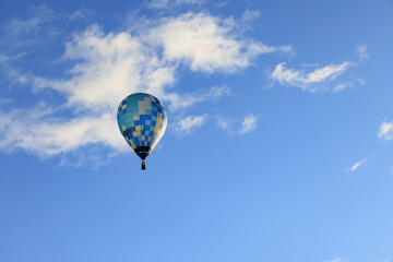 青い空に浮かぶ青い熱気球と白い雲