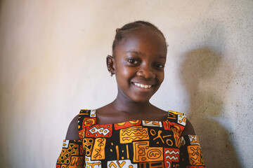 Pretty black African girl in a colorful traditional tribal dress smiling happily at the camera