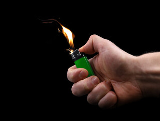 male hand using green lighter with flashflame and sparks isolated on black background - obrazy, fototapety, plakaty