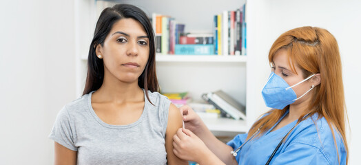 Latin american woman gets third vaccination against Covid 19 with nurse