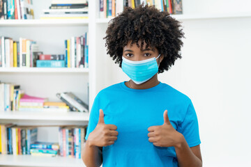 Optimistic african american woman with blue face mask