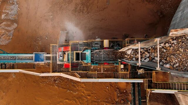 Crushing machinery, cone type rock crusher, conveying crushed granite gravel stone in a quarry open pit mining. Processing plant for crushed stone and gravel. Mining and Quarry mining equipment.