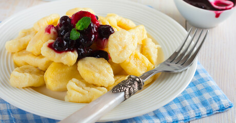 Cheese dumplings,gnocchi with sauce of black currants in a white ceramic plate for a healthy breakfast. Selective focus.