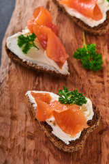 Mini sandwiches with salmon, curd cheese, parsley and rye bread in form of hearts. Valentine's day homemade creative food. Love breakfast design. Selective focus and copy space
