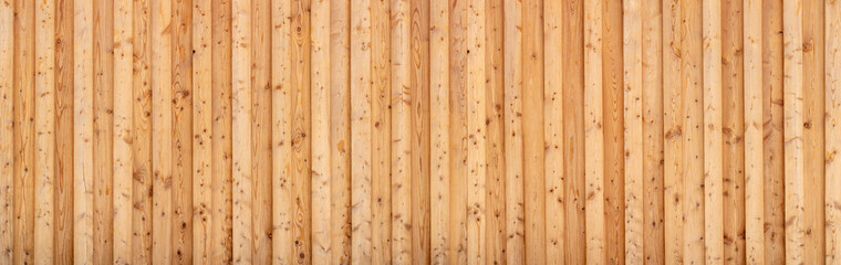 Hellbraune Panorama Holzwand aus vertikalen Fichtenholz Brettern mit starker Holzmaserung 