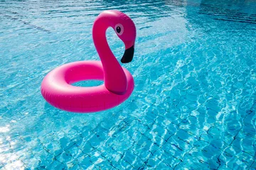 Poster Flamingo plastic. Pink inflatable flamingo in pool water for beach background. Trendy summer concept. © Maksym