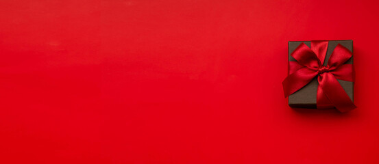 Image d& 39 un coffret cadeau avec un fond rouge uni et un ruban rouge