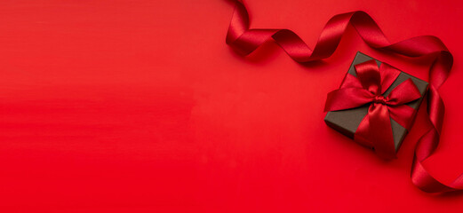 Afbeelding van een geschenkdoos met een effen rode achtergrond en een rood lint