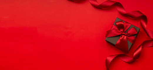 赤の無地の背景と赤いリボンを掛けたギフトボックスのプレゼントのイメージ