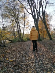 A man walking in a yellow down jacket in an autumn forest