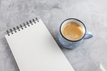 Mockup. Open sketchpad or notebook on artist desk workspace, coffee in blue retro style ceramic cup on gray background. Creative concept, empty page. Top view, copy space