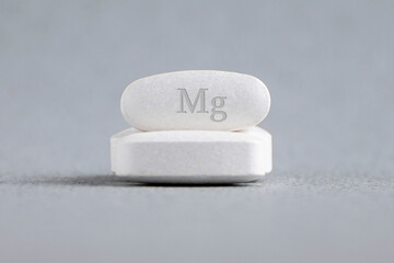 Tablets , vitamins with the abbreviation Mg ( magnesia, macro element magnesium ) on a light...
