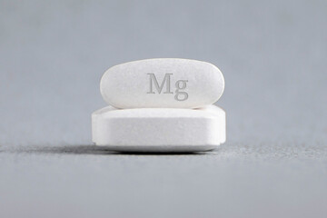 Tablets , vitamins with the abbreviation Mg ( magnesia, macro element magnesium ) on a light background. Copy space.