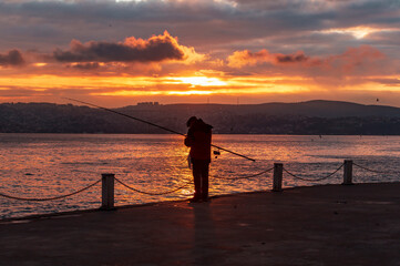 fisherman fishing on Bosporus İstanbul on a Foggy sunrise. Fishing rods on seaside. People jogging on coast. people walking in morning