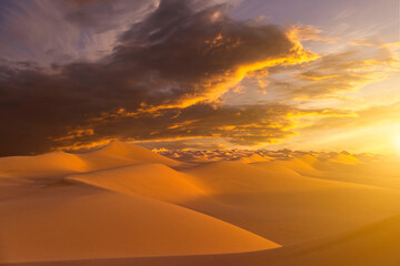 Naklejka na ściany i meble Sunset over the sand dunes in the desert. Arid landscape of the Sahara desert.