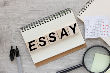 ESSAY. text on wood cubes. cubes on notebooks